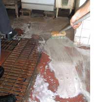飲食店厨房の汚れた床を厨房元気床側溝用を使用してブラシで清掃